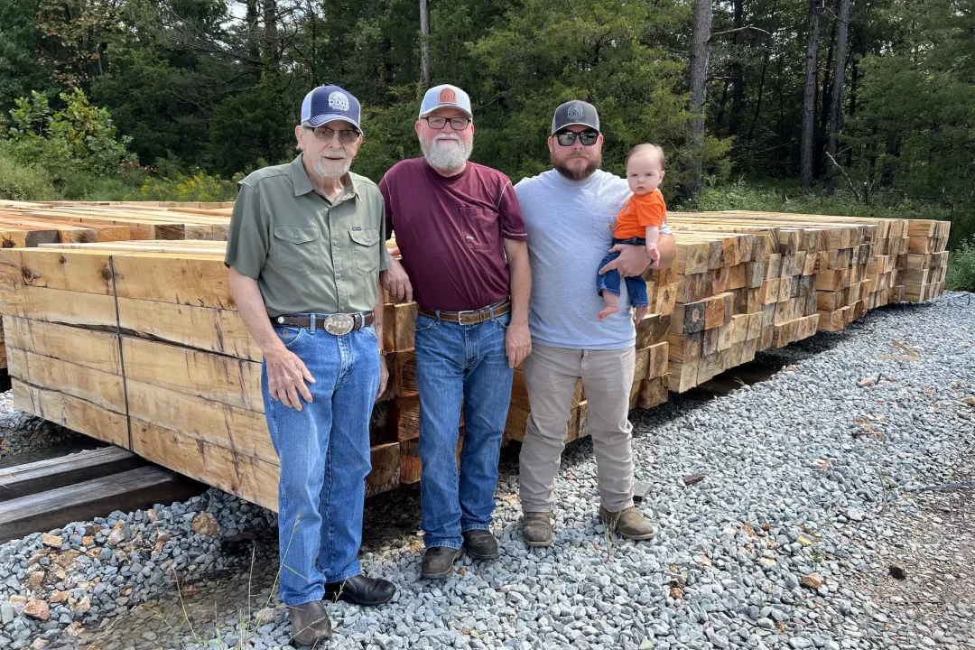 Four generations of the Hooper family standing in front of stacks of crossties.